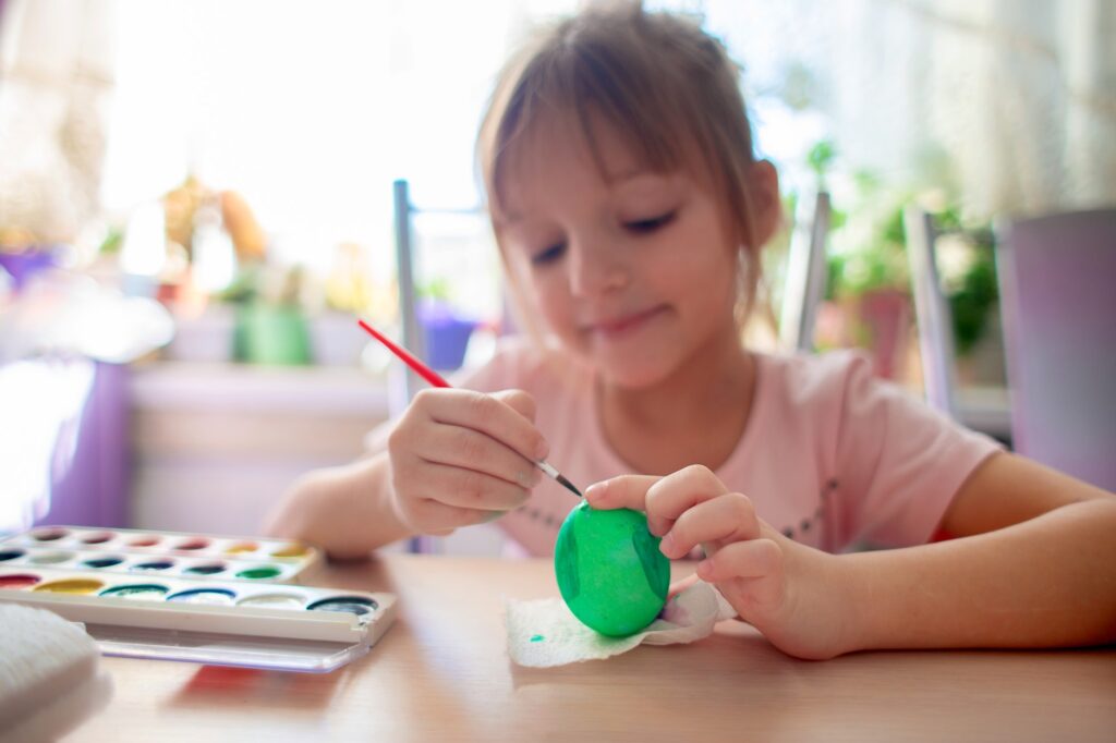 The girl painted the eggs for Easter. Easter eggs watercolor painting. Children's leisure